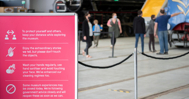 Family visiting Locomotion museum with a safety sign in foreground.